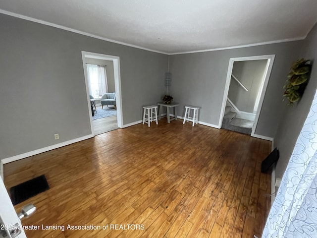 325 N Pennsylvania Ave, Lansing, MI 48912 - empty room featuring hardwood / wood-style floors, ornamental molding, stairway, and baseboards