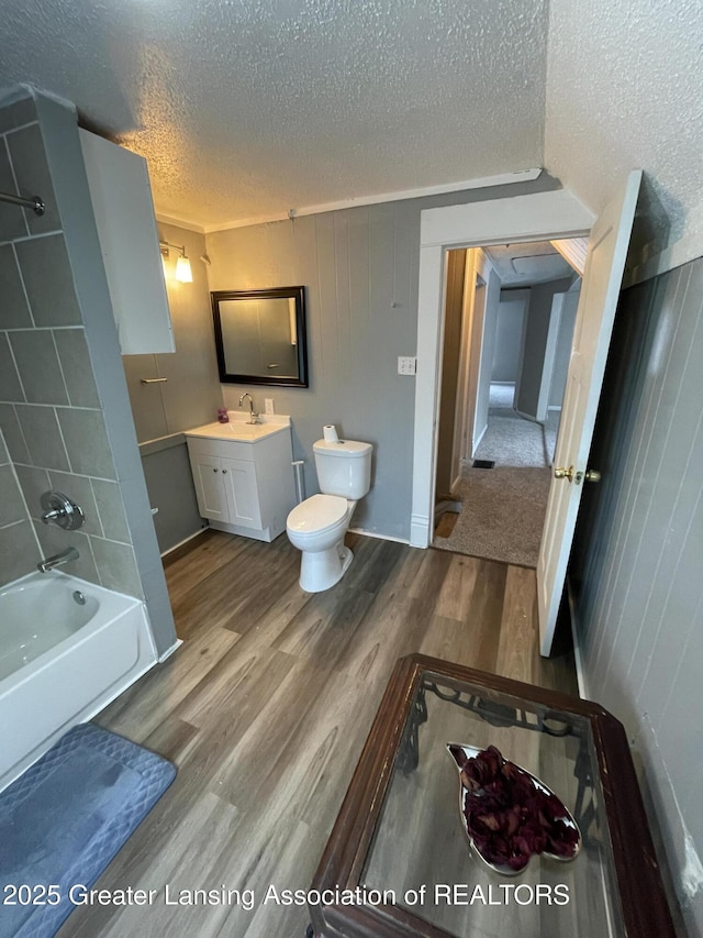 325 N Pennsylvania Ave, Lansing, MI 48912 - bathroom featuring a textured ceiling, wood finished floors, toilet, vanity, and a tub to relax in