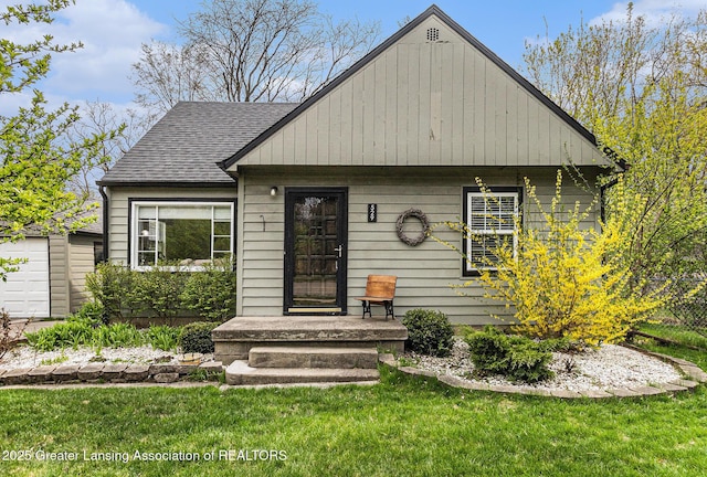 bungalow-style house featuring an outbuilding, a shingled roof, and a front yard