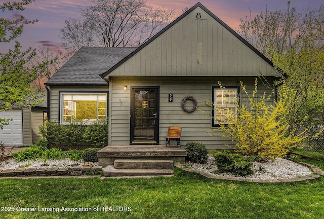 bungalow-style house with an outdoor structure, a lawn, and roof with shingles