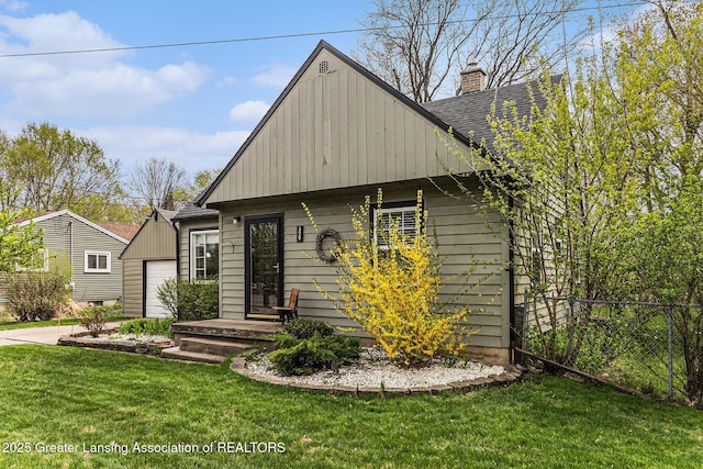 view of front facade featuring a front lawn, a garage, driveway, a chimney, and fence