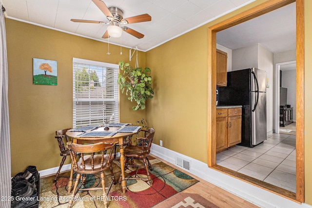 dining room featuring visible vents, ceiling fan, crown molding, and light wood finished floors