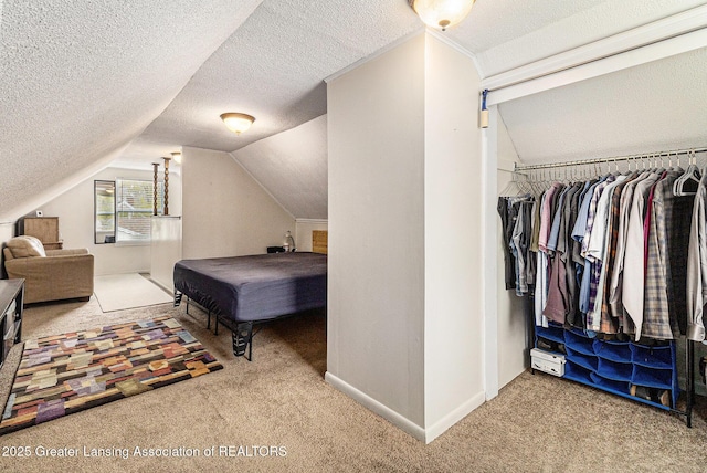bedroom featuring a textured ceiling, carpet flooring, and vaulted ceiling