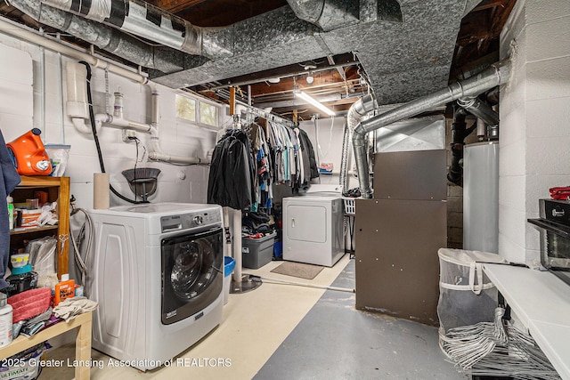 basement with concrete block wall, heating unit, and washing machine and clothes dryer