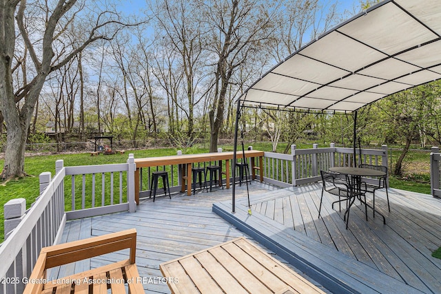 wooden deck featuring a yard, outdoor dining space, and fence