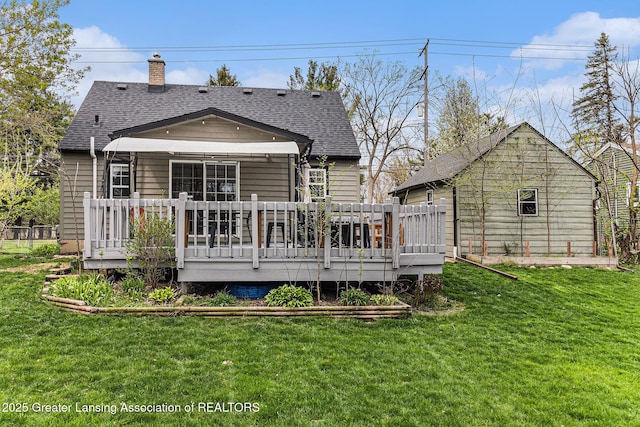 rear view of property featuring a chimney, a yard, a shingled roof, and a wooden deck