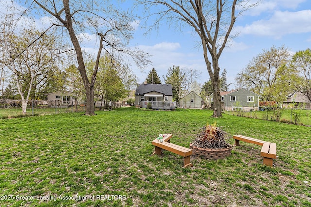 view of yard with a deck, an outdoor fire pit, and a fenced backyard