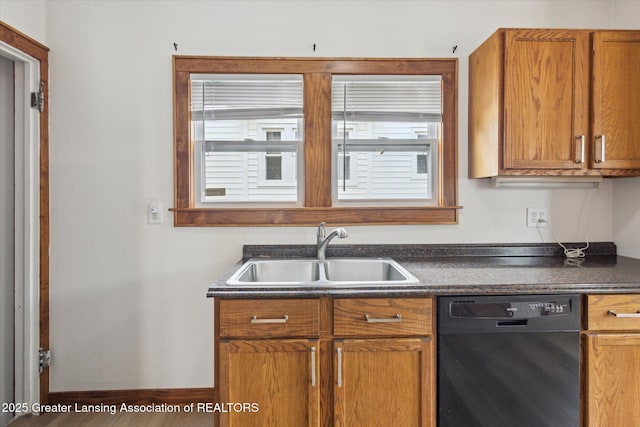kitchen with a healthy amount of sunlight, brown cabinetry, dark countertops, a sink, and black dishwasher