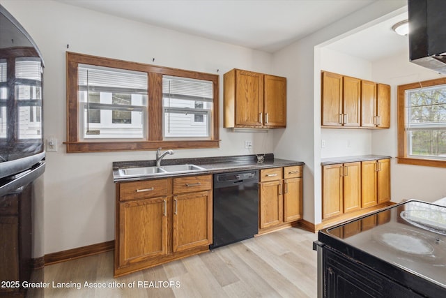 kitchen featuring light wood-style flooring, brown cabinets, a sink, and black appliances