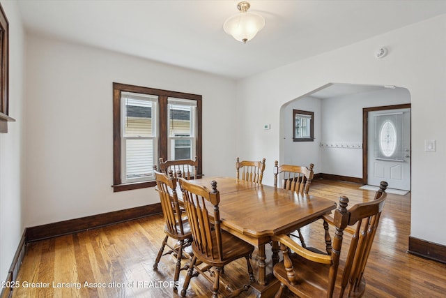 dining room with baseboards, arched walkways, and hardwood / wood-style flooring
