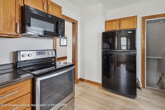 kitchen featuring baseboards, brown cabinetry, black appliances, and light wood-style floors