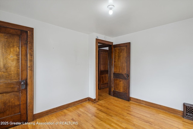 spare room featuring baseboards, light wood finished floors, and visible vents