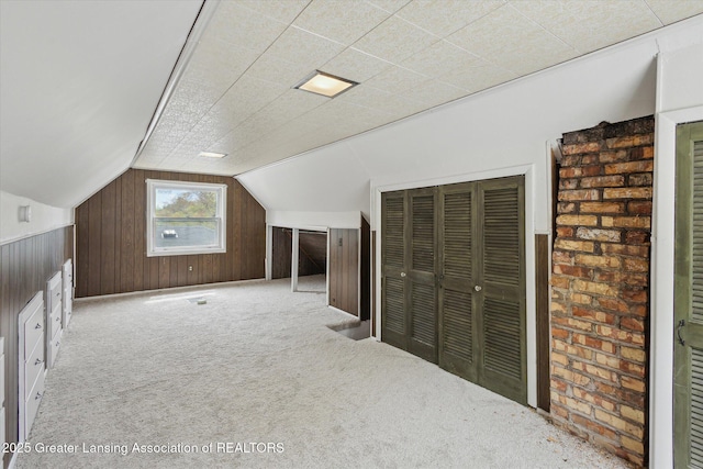 bonus room featuring carpet floors, wood walls, and lofted ceiling