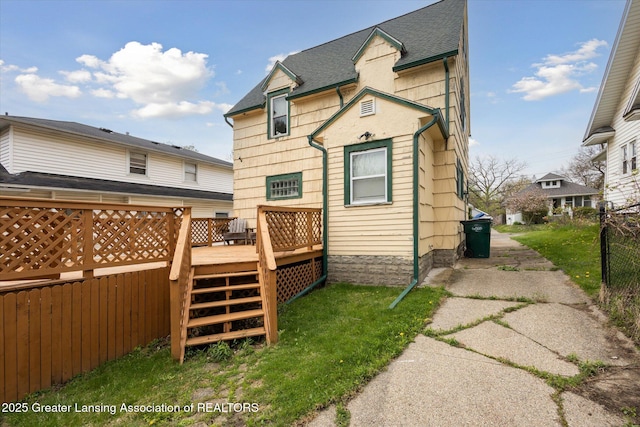 rear view of house with fence, a wooden deck, roof with shingles, and stairway