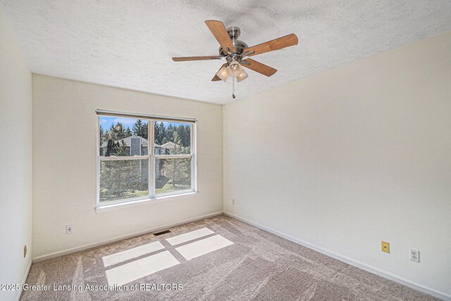 empty room featuring a textured ceiling, visible vents, ceiling fan, and carpet floors