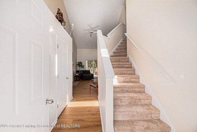 stairway featuring a ceiling fan, high vaulted ceiling, and wood finished floors