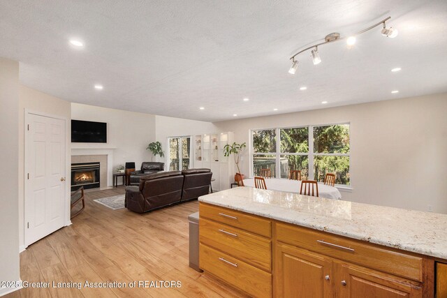 kitchen with light stone countertops, a tile fireplace, recessed lighting, and light wood-style floors