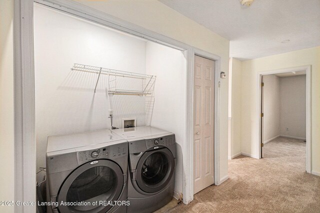 clothes washing area with light colored carpet, separate washer and dryer, baseboards, and laundry area