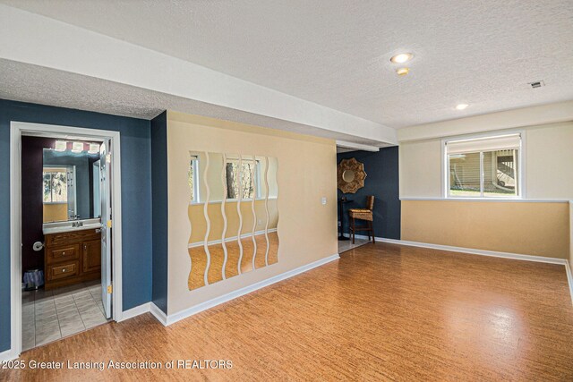 interior space featuring baseboards, a textured ceiling, visible vents, and light wood-style floors