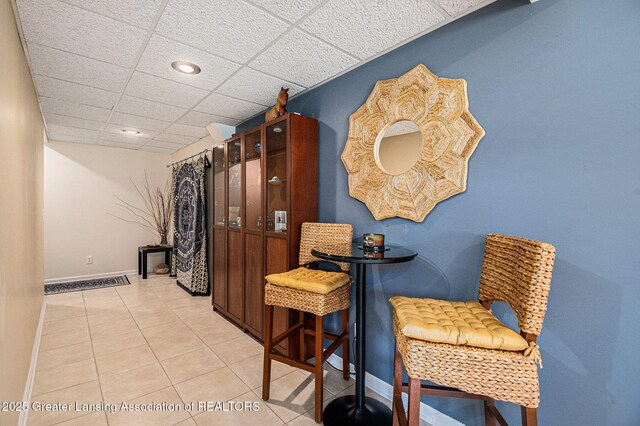 dining space with light tile patterned floors, recessed lighting, a drop ceiling, and baseboards