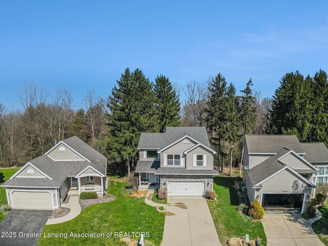 view of front of home featuring stone siding, an attached garage, a front yard, and concrete driveway