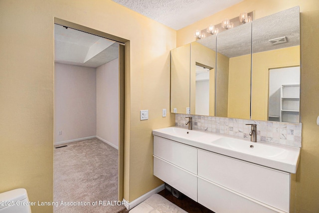 bathroom with a sink, double vanity, visible vents, toilet, and backsplash