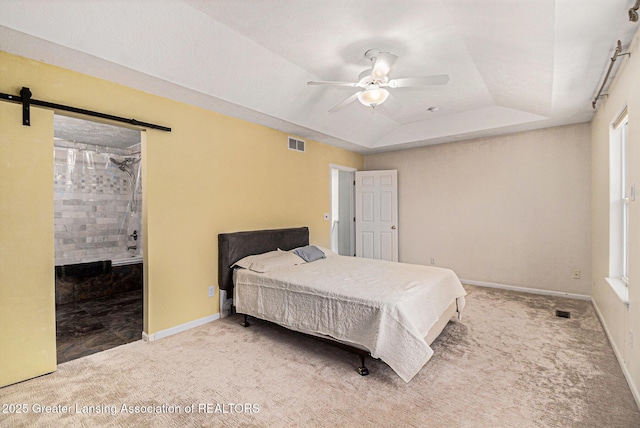 carpeted bedroom featuring a raised ceiling, visible vents, a barn door, and baseboards
