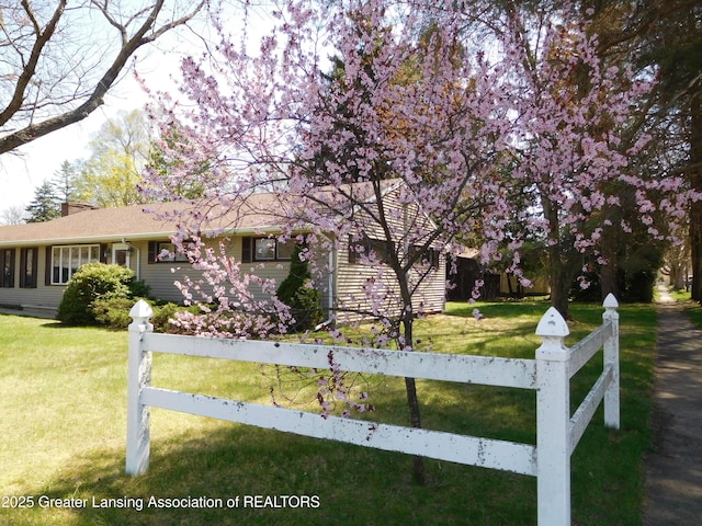 view of front of house with a chimney, fence, and a front yard