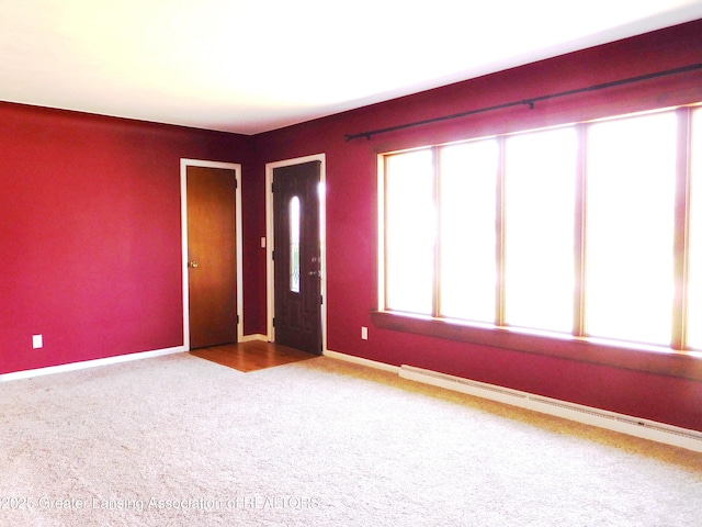 carpeted spare room with a baseboard heating unit and baseboards