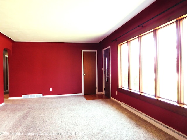 spare room with arched walkways, baseboards, visible vents, carpet floors, and a baseboard radiator