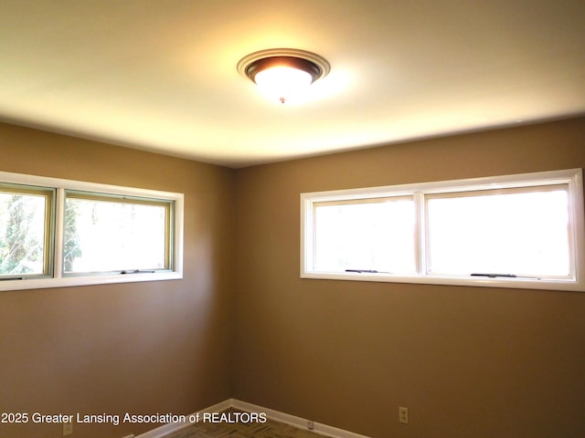 spare room featuring baseboards and plenty of natural light