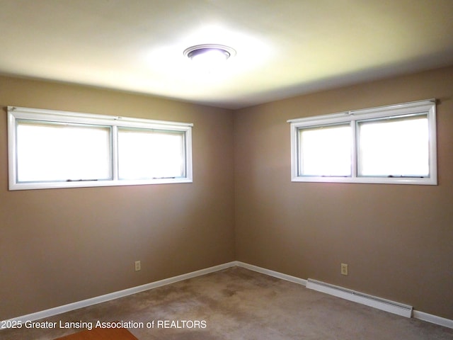 spare room with carpet floors, baseboards, a wealth of natural light, and baseboard heating