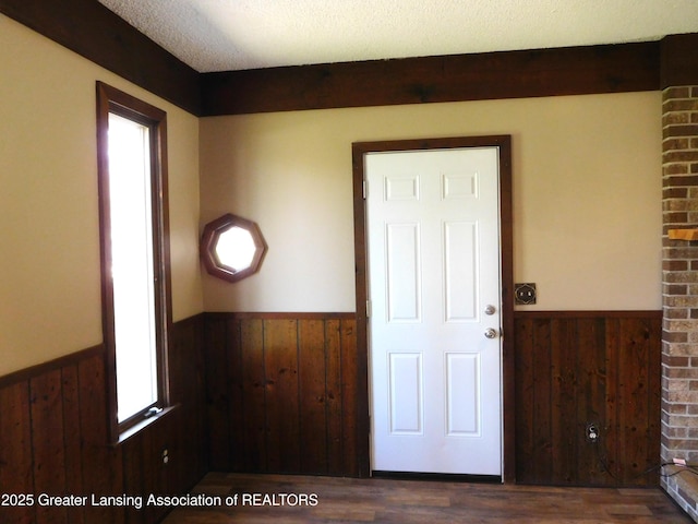 doorway to outside with wainscoting, wood finished floors, and wood walls