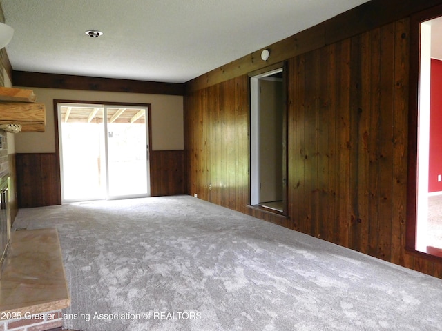unfurnished living room with wood walls, a fireplace, and carpet floors