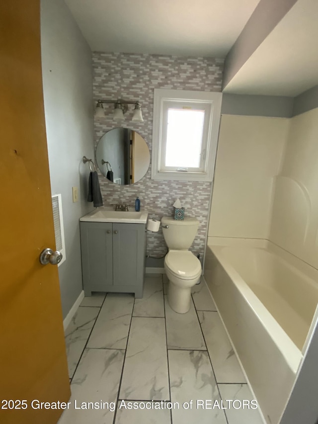 bathroom featuring vanity, a tub to relax in, toilet, and marble finish floor