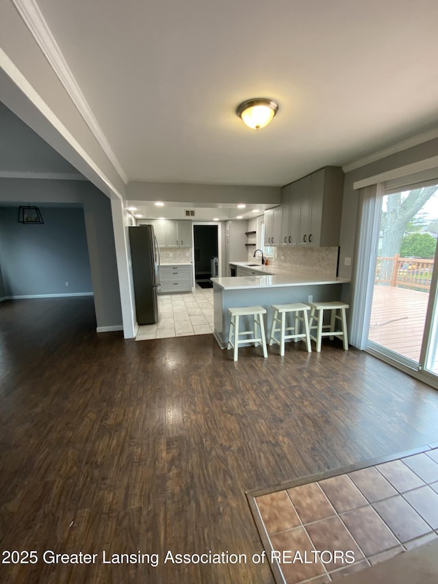 kitchen featuring crown molding, a peninsula, freestanding refrigerator, and light wood-type flooring