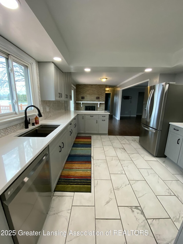 kitchen featuring a sink, appliances with stainless steel finishes, light countertops, recessed lighting, and marble finish floor