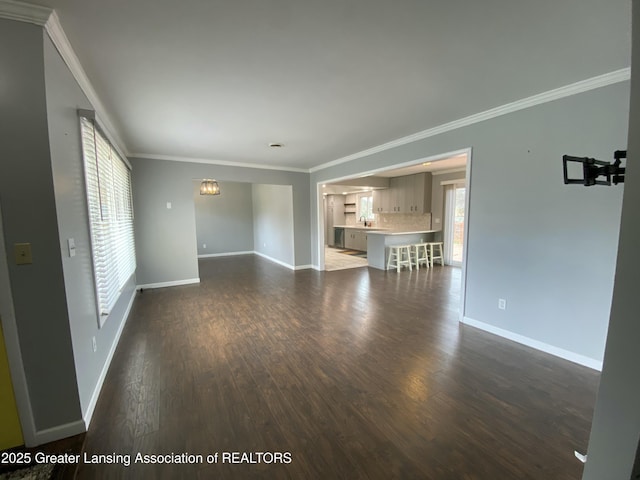 unfurnished living room featuring crown molding, dark wood-type flooring, and baseboards