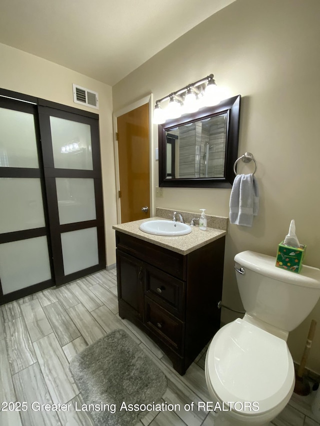 bathroom featuring visible vents, toilet, and vanity
