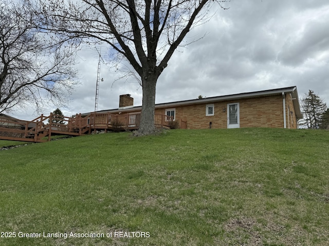 back of house with a chimney, a yard, and a deck