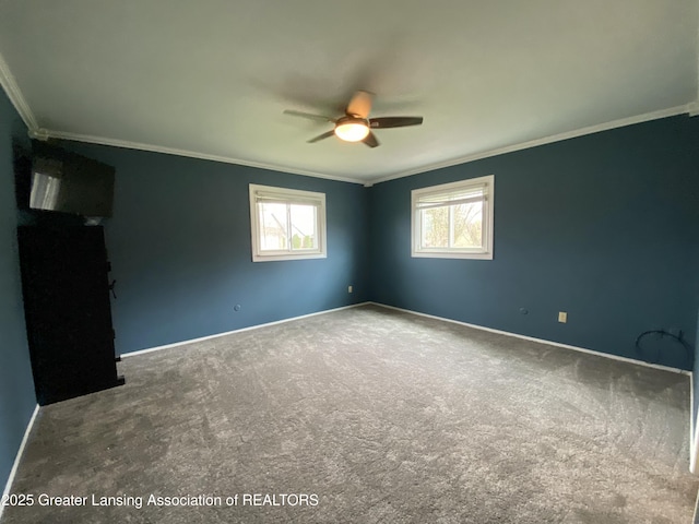 carpeted empty room with ceiling fan, ornamental molding, and baseboards