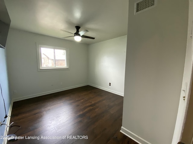 empty room featuring visible vents, a ceiling fan, dark wood-style floors, and baseboards