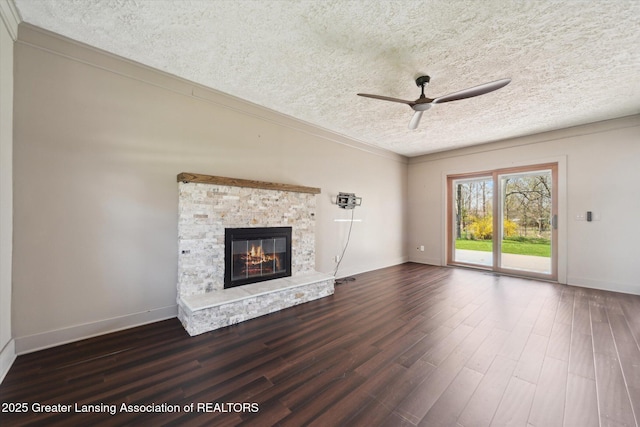 unfurnished living room featuring a fireplace, baseboards, ceiling fan, dark wood-type flooring, and a textured ceiling