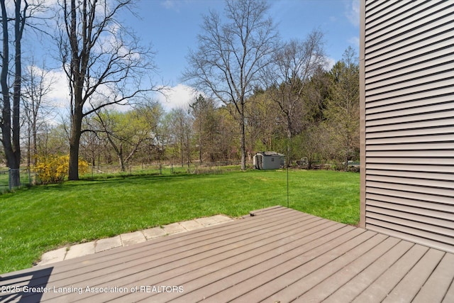wooden deck featuring a storage shed, an outbuilding, a yard, and a fenced backyard