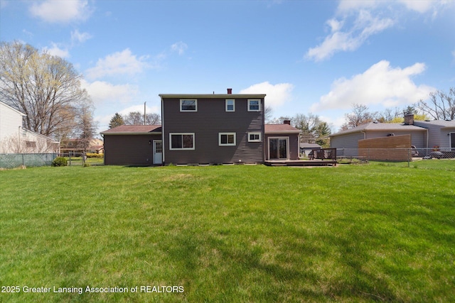 rear view of property featuring a yard, fence, a wooden deck, and a chimney