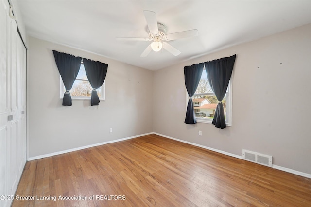unfurnished room with a ceiling fan, baseboards, visible vents, and light wood finished floors