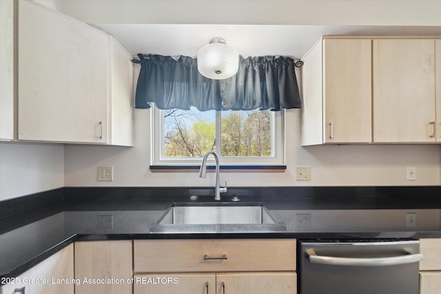 kitchen with stainless steel dishwasher, a sink, light brown cabinets, and dark countertops