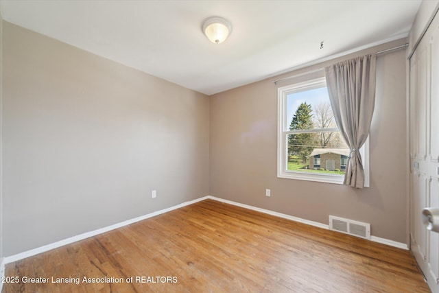empty room featuring baseboards, light wood-style flooring, and visible vents