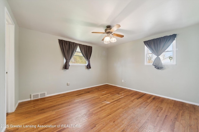 spare room with light wood-style floors, baseboards, a ceiling fan, and visible vents