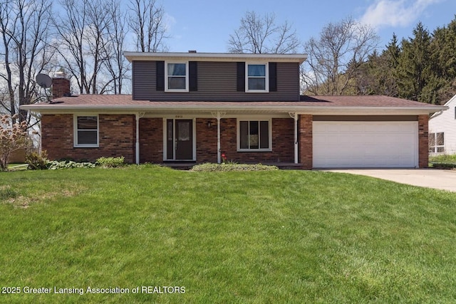 traditional-style home with a front yard, a chimney, brick siding, an attached garage, and driveway